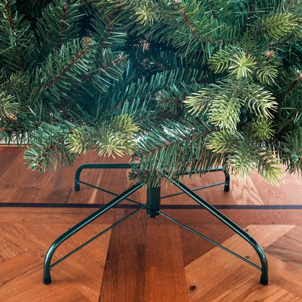 Detailaufnahme eines künstlichen Weihnachtsbaums mit Metallständer auf einem Holzboden