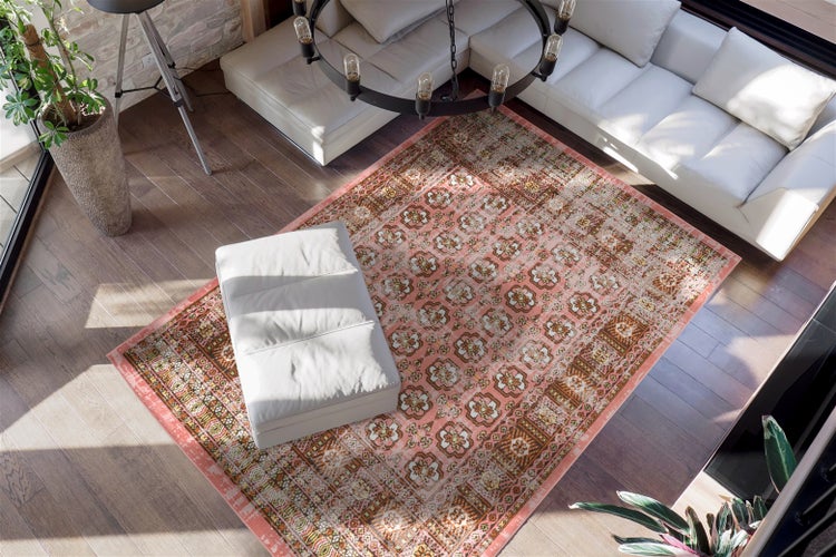 Großzügiges Wohnzimmer mit einem Orientteppich mit rosa-beigem Blumenmuster auf dunklem Holzboden, weißem Ledersofa und Hocker.