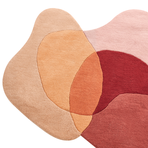 Abstrakt geformter Teppich mit organischen, überlappenden Mustern in Beige, Orange und Rot. Weiche, getuftete Textur.