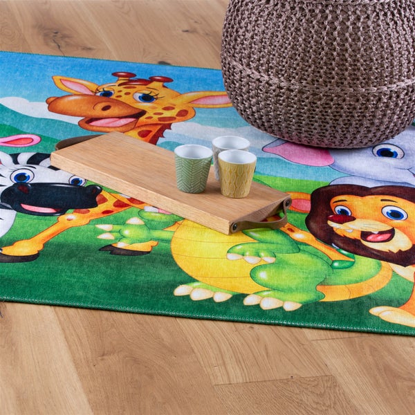Bunter Kinderteppich mit Tiermotiven wie Löwe, Giraffe und Zebra auf Holzboden, mit Holztablett und Strickhocker.