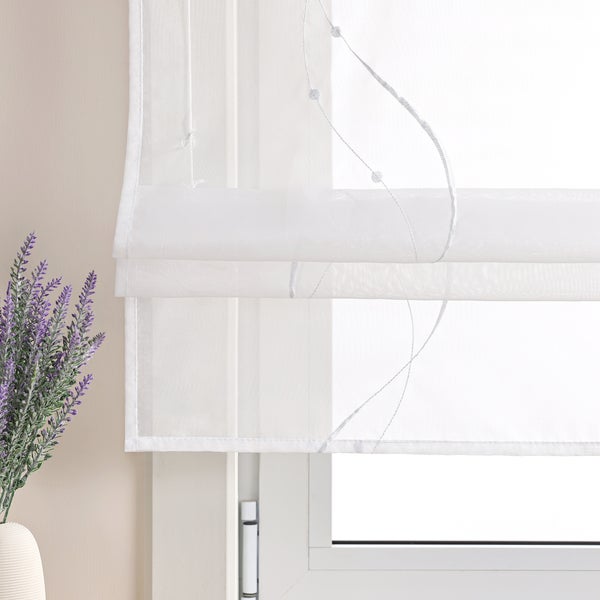 Dekoratives Faltrollo mit floralem Design vor einem Fenster