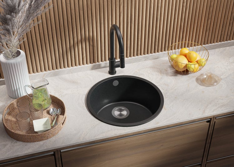 Küchenszene mit rundem Spülbecken, Wasserhahn, Obst und Accessoires auf einer Arbeitsplatte