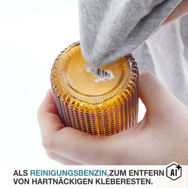 Hände entfernen mit einem Tuch Klebereste vom Boden eines Glasgefäßes mithilfe von Reinigungsbenzin.