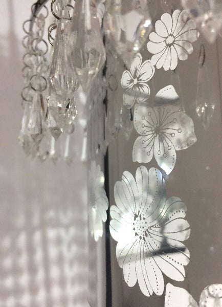 Detailaufnahme einer Lampe mit Blumenmuster und Kristallanhängern.