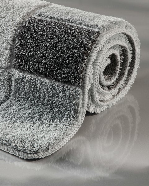 Zusammengerollte Badematte mit Karomuster und weichem Hochflor.