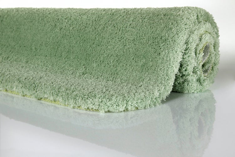 Hochflor-Badematte in Grün, eingerollt.