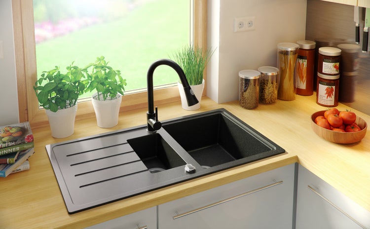 Küchenszene mit schwarzer Spüle, Armatur und Küchenutensilien auf einer Arbeitsplatte.