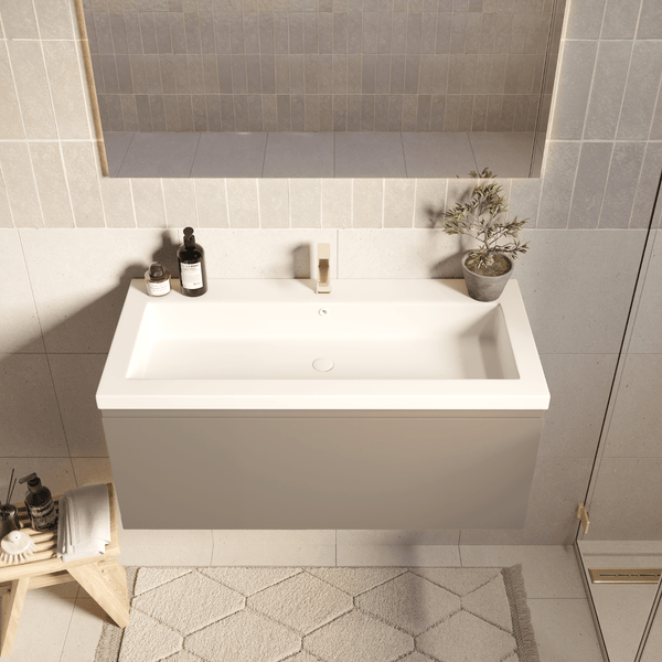 Moderner Badezimmer-Waschtisch mit weißem rechteckigem Waschbecken und hängendem Unterschrank in Grau vor einer gefliesten Wand.