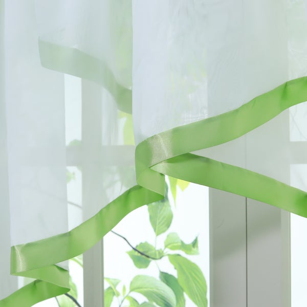 Gardine mit Zierband vor Fenster