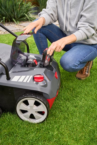Eine Person setzt einen 18 Volt oder 36 Volt Akku in das Akkufach eines AL-KO Akku-Rasenmähers ein.