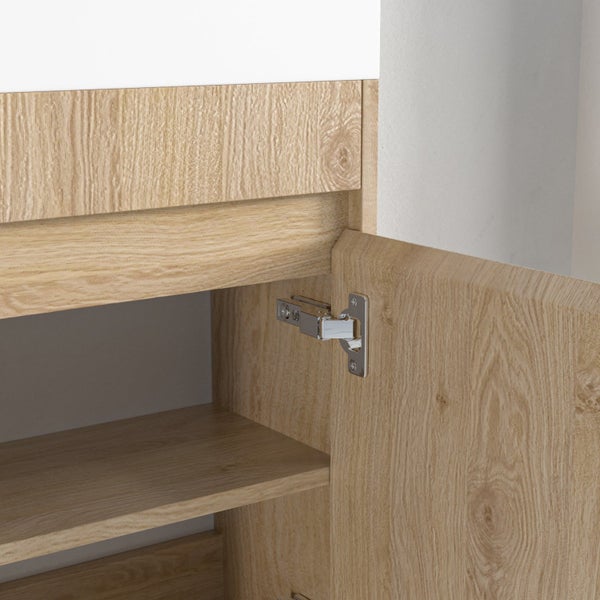 Detailansicht eines offenen Waschtischunterschranks in Eichenholzoptik mit Metallscharnier.