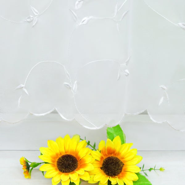 Dekoratives Fenster mit Stickereien und zwei Sonnenblumen