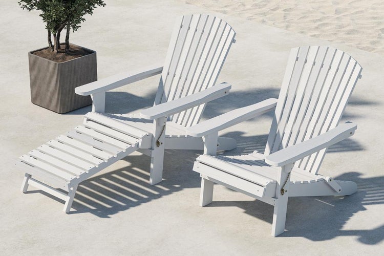 Zwei weiße Adirondack-Stühle aus Holz mit Fußstütze im Garten.