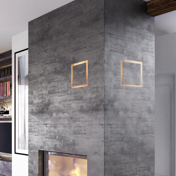 Moderne quadratische Wandleuchte in minimalistischem Design an einer strukturierten Wand über einem Kamin in einem Wohnzimmer.