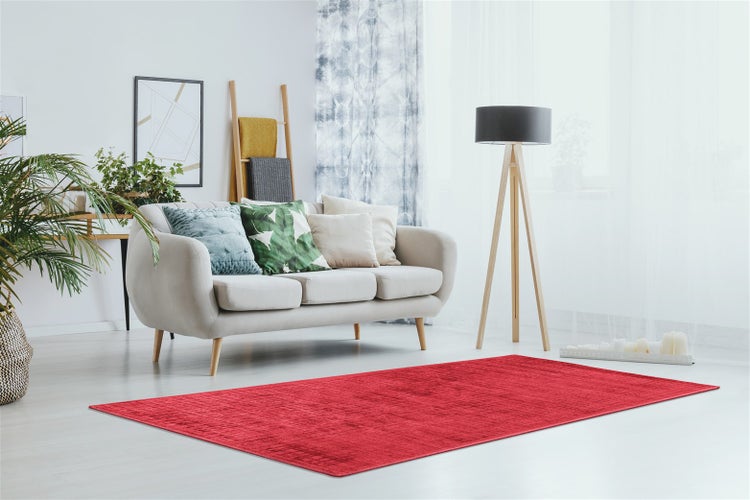 Roter Teppich in einem hellen Wohnzimmer mit beigem Sofa und einer Stehlampe mit Holzstativ.