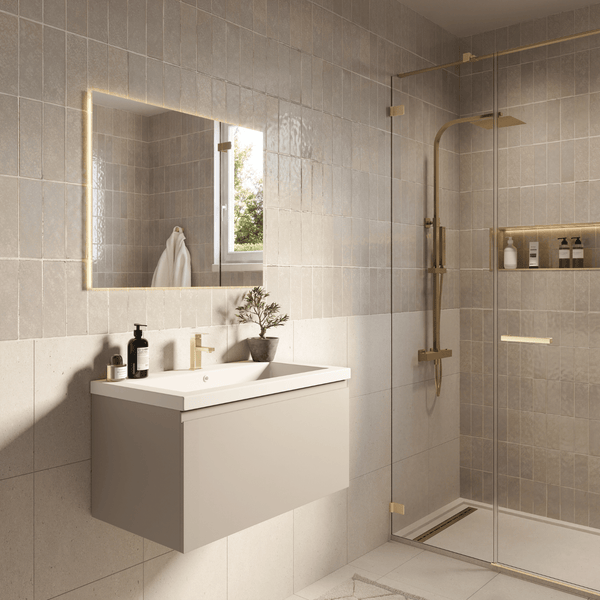 Modernes Badezimmer mit hängendem Waschtischunterschrank, goldener Armatur, beleuchtetem Spiegel und Dusche mit goldfarbenen Armaturen.