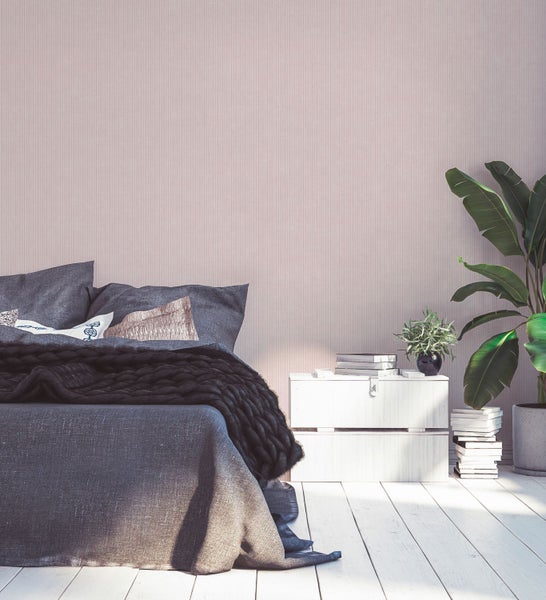 Schlafzimmer mit Bett, Nachttisch, Zimmerpflanze und Bücherstapel für eine helle und freundliche Atmosphäre.