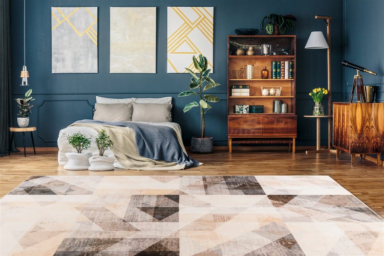 Modernes Schlafzimmer mit großem Teppich mit geometrischem Dreiecksmuster in Beige und Braun, niedrigem Bett, dunkelblauen Wänden und Holzmöbeln.