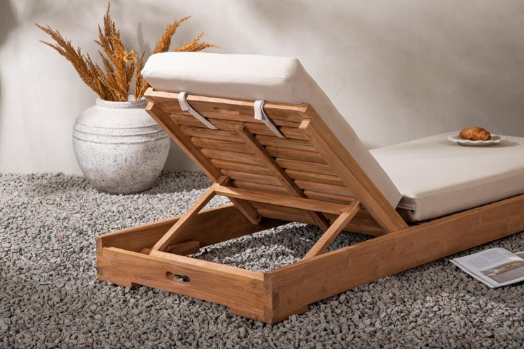 Holzliege mit hellen Auflagen im Garten