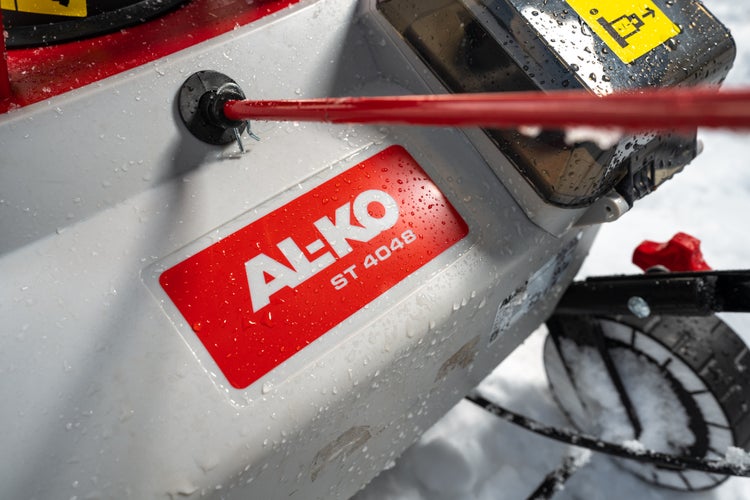 Nahaufnahme einer AL-KO ST 4048 Schneefräse mit Logo und Typenbezeichnung bei winterlichen Bedingungen.