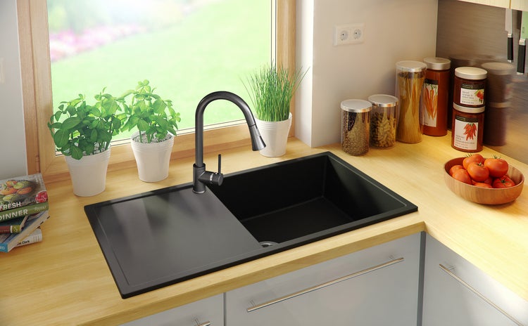 Schwarze Küchenspüle mit Armatur in einer hellen Küche