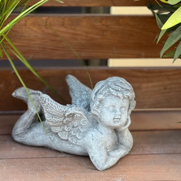 Dekorative Engelsfigur aus Stein in liegender Position als Gartenfigur für den Außenbereich