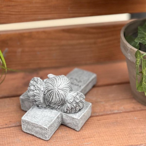 Grabschmuck in Kreuzform mit einem schlafenden Engel aus witterungsbeständigem Material als Dekoration für den Garten oder den Friedhof.
