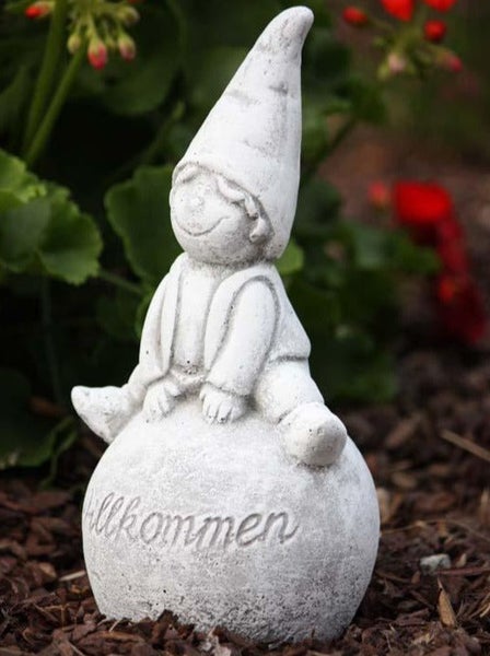 Steinfigur Gartenzwerg sitzend auf einer Kugel mit Willkommen Schriftzug fuer die Gartendekoration