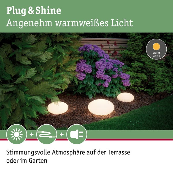 Mehrere beleuchtete Papiersterne in Gold und Weiß hängen vor einer Ziegelwand und erzeugen eine festliche Atmosphäre.
