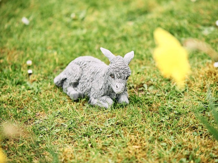 Liegende Esel Gartenfigur aus Kunststein zur Dekoration im Außenbereich auf einer Wiese.