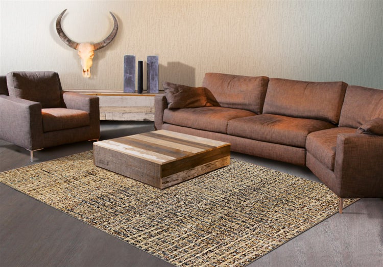 Wohnzimmer mit Ecksofa, Sessel, quadratischem Holztisch und gemustertem Teppich auf Holzboden vor einer Wand mit Büffelschädel.