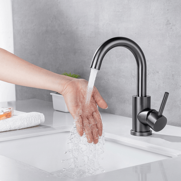 Moderne Einhebel Waschtischarmatur in einer Badezimmerszene, Wasser fließt aus dem Auslauf über eine Hand in das Waschbecken.