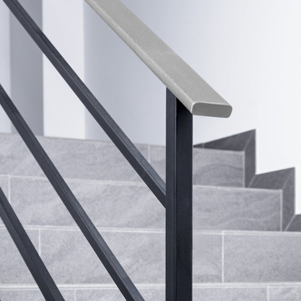 Treppengeländer mit schwarzem Metallpfosten, diagonalen Streben und einem grauen Handlauf vor gefliesten Treppenstufen.