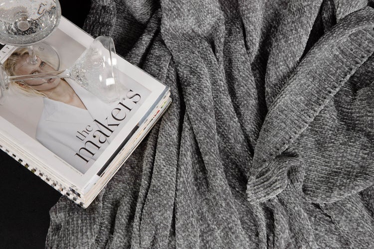 Graue Kuscheldecke neben Zeitschrift und Weingläsern