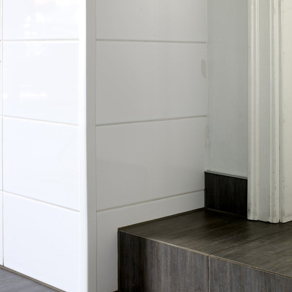 Detailansicht eines Badezimmers mit weißen Wandfliesen und dunklen Bodenfliesen.