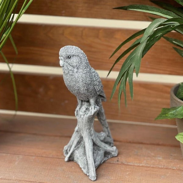 Steinfigur Wellensittich als Gartendekoration auf einem Ast sitzend