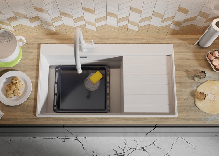 Küchenspüle mit Backblech, Spülmittel und Küchenutensilien auf einer Küchentheke.