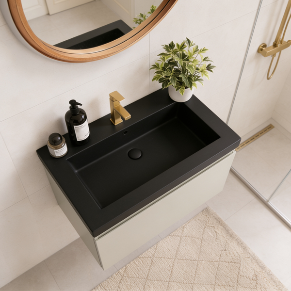 Modernes Badezimmer mit wandhängendem Waschtisch, mattschwarzem Waschbecken, goldener Armatur, rundem Holzspiegel und Zimmerpflanze.