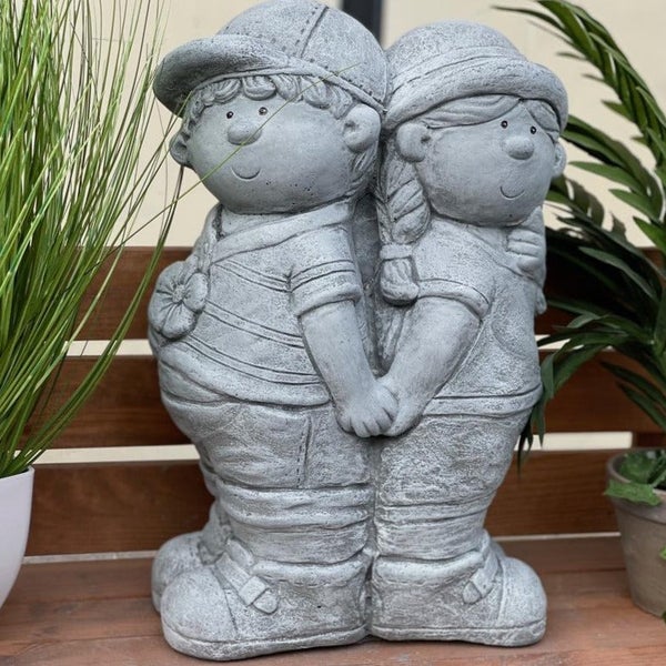 Steinstatue von zwei Kindern, die sich an den Händen halten, als dekorative Gartenfigur für den Außenbereich.