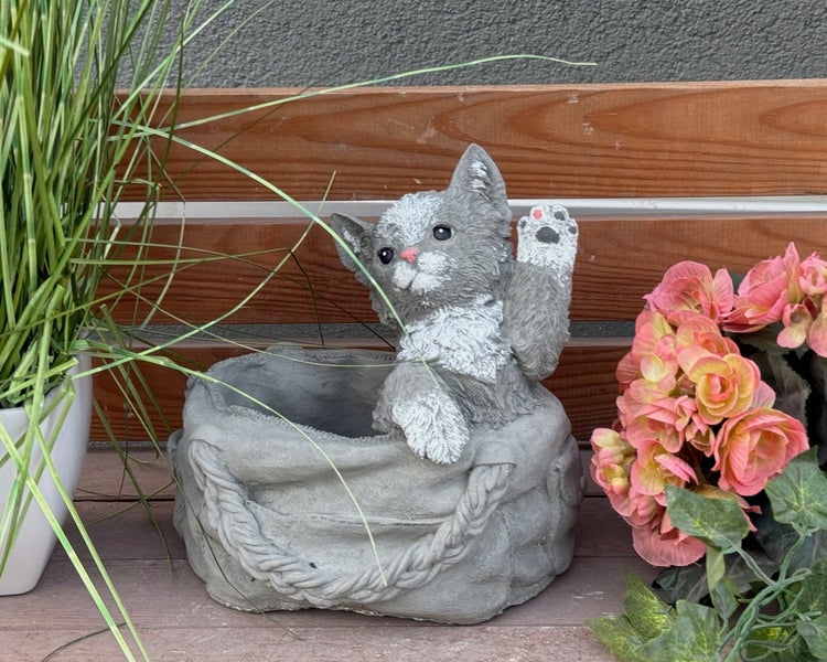 Dekorativer Pflanztopf aus Steinguss in Form einer Katze im Korb, wetterfeste Gartenfigur.