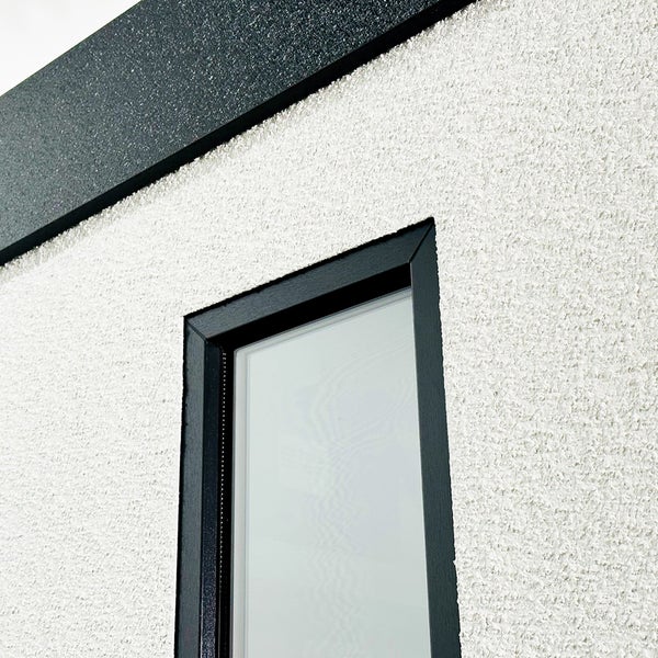 Nahaufnahme einer Fassade mit Fensterrahmen und Abschlussleiste