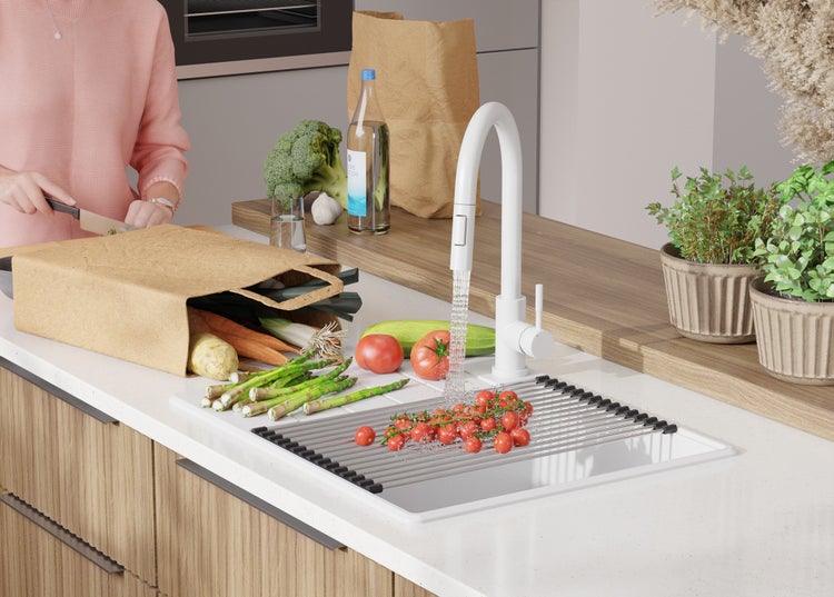 Küchenszene mit Spüle, Armatur, Gemüse und Person