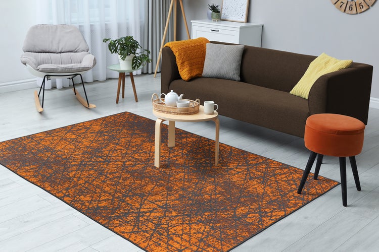 Modernes Wohnzimmer mit orange-grauem Teppich, braunem Sofa, Holz-Couchtisch, grauem Schaukelstuhl und orangefarbenem Hocker. Hell und organisiert.