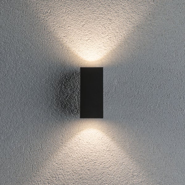 Rechteckige Wandleuchte mit Up and Down Lichteffekt an einer strukturierten Fassade.