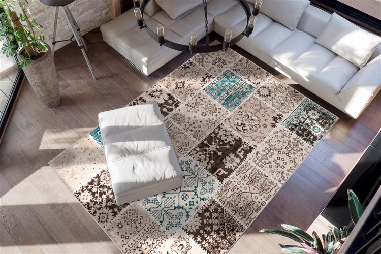 Moderner Teppich im Patchwork-Design mit beige, braun und türkisen Mustern in einem hellen Wohnzimmer mit weißem Ledersofa und Holzboden.