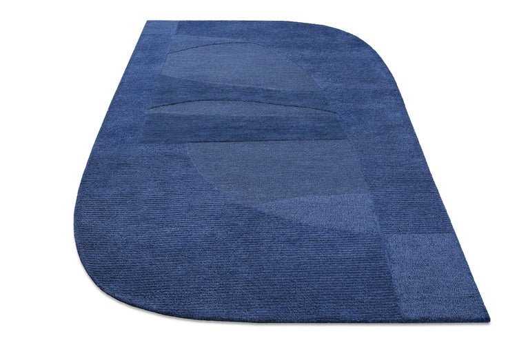 Hell eingerichtetes Wohnzimmer mit einem strukturierten In- und Outdoor-Teppich auf Holzfußboden, einem Sofa und einem Sessel.