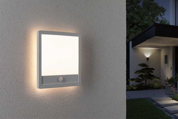 Quadratische LED Außenwandleuchte mit Bewegungsmelder an einer Hausfassade bei Dämmerung.