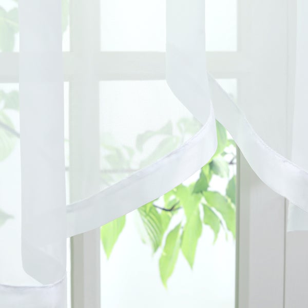 Weißer, transparenter Gardinenschal vor einem Fenster