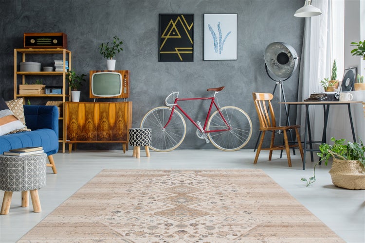 Beiger Teppich mit geometrischem Muster in einem hellen, geräumigen Zimmer mit Retro-Möbeln, blauem Sofa und Vintage-Dekoration.