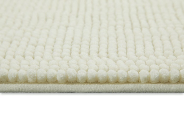 Nahaufnahme einer weichen Badematte mit Chenille-Struktur in Cremeweiß.